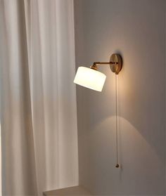 a wall light that is on the side of a wall next to a white curtain