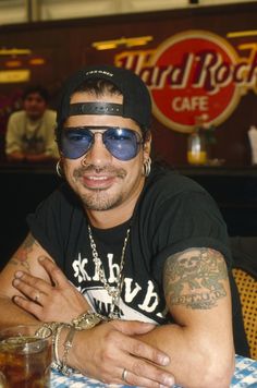 a man sitting at a table with his arms crossed and wearing sunglasses on top of him