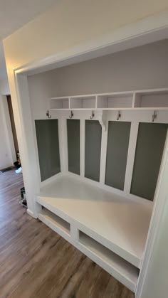 an empty room with some white shelves and gray doors on the wall, in front of a hardwood floor