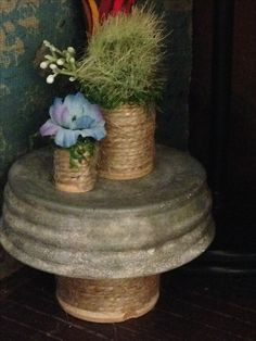 two vases with flowers are sitting on a pedestal