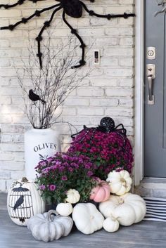 a halloween porch decoration with pumpkins and flowers in front of a spider on the wall