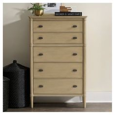 a wooden chest of drawers next to a plant