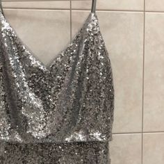 a silver sequin dress hanging on a tiled wall