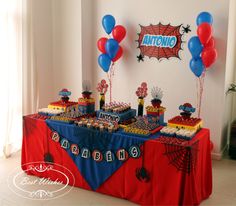 a table topped with lots of desserts and balloons in the shape of spiderman