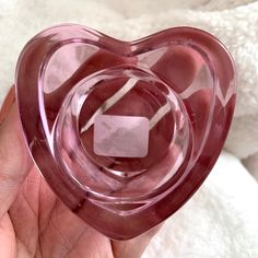 a pink heart shaped glass object in someone's hand