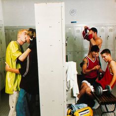 three men in lockers with one drinking from a water bottle