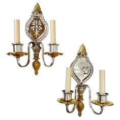 two silver and gold wall sconces with candles