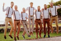 a group of young men jumping in the air with their arms around each other while wearing suspenders and bow ties