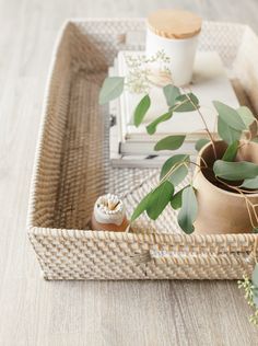 a wicker tray with some plants and books on the top, along with other items