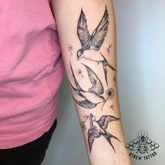 a woman's arm with three birds on it and one bird flying in the air