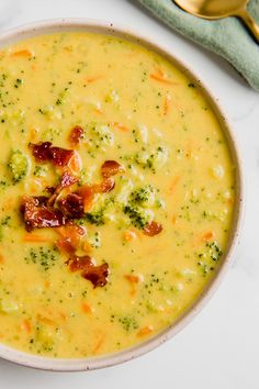 a white bowl filled with broccoli and bacon soup on top of a table