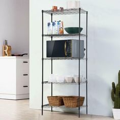 a black shelving unit with three shelves and baskets on the bottom shelf, next to a cactus