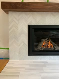 a fireplace with a fire burning in it's mantle and wood on the floor