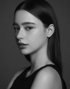 black and white photo of a woman with long dark hair wearing a tank top looking at the camera