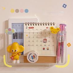 a desk calendar with an elephant figurine next to it and pens on the table