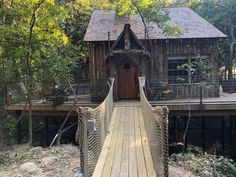 a small wooden house in the woods with a rope bridge leading to it's entrance