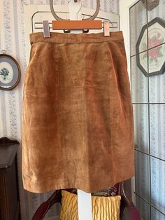 This fitted skirt is made of very soft suede leather in medium rusty brown. It fastens in the back with a snap and zipper and has a small back slit, and is lined with brown silky lining. The label reads "H.E.R."; marked size 11/12. The measurements, taken with the skirt lying flat, are: waist, 13 1/2 inches; hips, 19 1/2 inches; length, 21 1/2 inches; bottom edge, 19 inches. In good vintage condition. Brown Suede Skirt, Short Pencil Skirt, Suede Shorts, Skirt Knee Length, Vintage Suede, Suede Skirt, Fitted Skirt, Knee Length Skirt, Vintage Brown