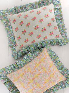 three pillows with ruffled edges and flowers on them