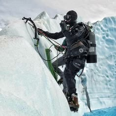 a man climbing up the side of a snow covered mountain next to an iceberg