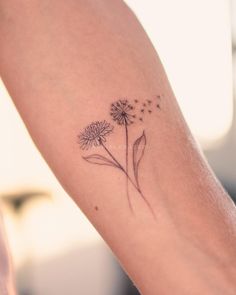 a woman's arm with a dandelion tattoo on it