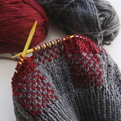 two skeins of yarn are next to each other with knitting needles in them