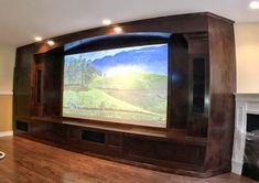 a large screen in the middle of a room with wood flooring and built - in fireplace