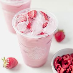 two cups filled with ice and strawberries next to a bowl full of strawberries