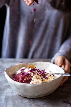 a person is spooning food out of a white bowl with red cabbage in it