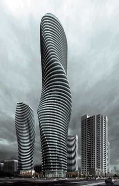 two tall skyscrapers in the middle of a cloudy sky with cars driving past them