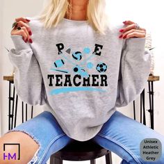 a woman sitting on top of a stool wearing a sweatshirt with the words rise teacher