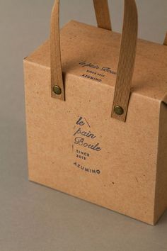 a brown paper bag with handles and string on the handle is sitting in front of a gray background