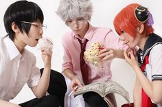 three people are sitting on the floor and one is eating food while the other looks at an open book