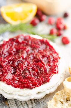 cranberry goat cheese appetizer on a plate with bread and lemons in the background