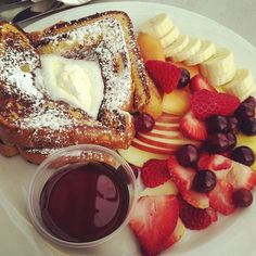 a white plate topped with french toast and fruit