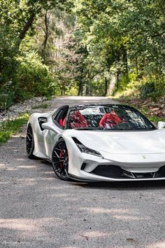 a white sports car parked on the side of a road in front of some trees