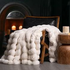 a white blanket sitting on top of a wooden table next to a chair and fire place