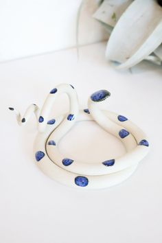 a white snake with blue spots on it's body sitting on top of a table