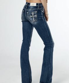 The Miss Me Women's Scalloped Edge Cross Embroidered Mid-Rise Bootcut Jeans feature a medium dark-wash and a mid-rise fit. They are adorned with white, silver, and blue embroidery, as well as mini rhinestone and translucent sequin details. The jeans also include a white leather logo brand patch and rhinestone rivets for added style. 5-pocket design Slight distressing on back pocket and front belt loop area Slight Fading Front Rise: 9.5" Back Rise: 14" Inseam: 34" 52% Cotton 27% Lyocell 20% Polyester 1% Elastane Gentle machine wash with like colors in cold water Tumble dry low Jeans With Cross On The Back, Embroidered Low Rise Jeans, Low Rise Miss Me Jeans, Country Girl Jeans, Missme Jeans, Jeans With Rhinestones, Mexican Jeans, Mid Rise Jeans Outfit, Surprise Dance Outfits