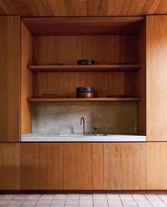 an empty kitchen with wooden cabinets and white tile flooring on the walls, along with a stainless steel faucet