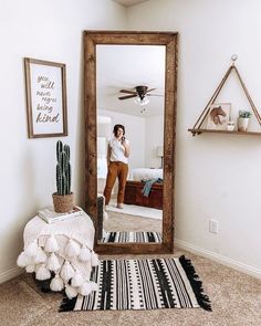 a woman is taking a selfie in front of a mirror with a cactus on the floor