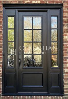 a black double door with two sidelights and glass panels on the front of a brick building