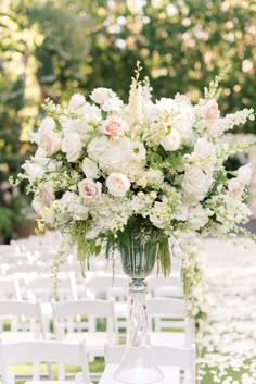 a vase filled with white and pink flowers on top of a table covered in chairs