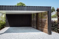 an open garage door with wooden slats on the side and gravel ground below it