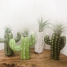 three green and white cactus planters sitting on top of a wooden table next to each other