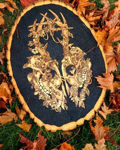 a tree stump with an image of two skulls on it in the grass surrounded by leaves