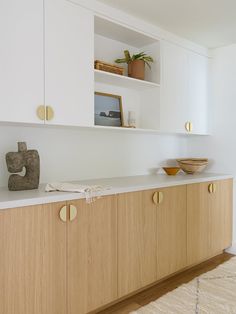 a white kitchen with wooden cabinets and counter tops, including a bowl on the counter