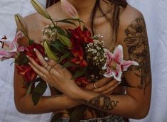 a woman with tattoos holding flowers in her hands