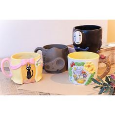 three coffee mugs with designs on them sitting on a table next to each other