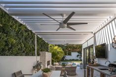 an outdoor kitchen and dining area with a ceiling fan in the middle of the room