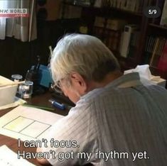 an older man sitting at a desk in front of a book